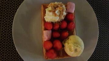 A plate with a waffle, strawberries, and a scoop of ice cream.