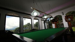 A pool table in a room with large windows, decorative iron railings, and hanging lamps. - Mahaweli Regent Hotel (Kandy)
