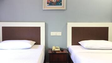 Quarto de hotel com duas camas, uma mesa de cabeceira com telefone e um quadro na parede.