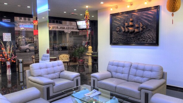 A hotel lobby with two sofas, a glass coffee table, and a framed ship painting on the wall. - CK Hotel (Malacca City)
