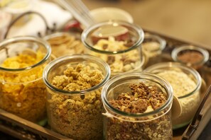 Une variété de barres de céréales et de granola présentées dans des bocaux en verre, disposées sur un plateau.