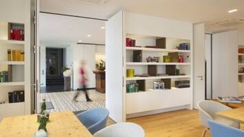 A modern library with open shelving, a wooden table, and chairs.