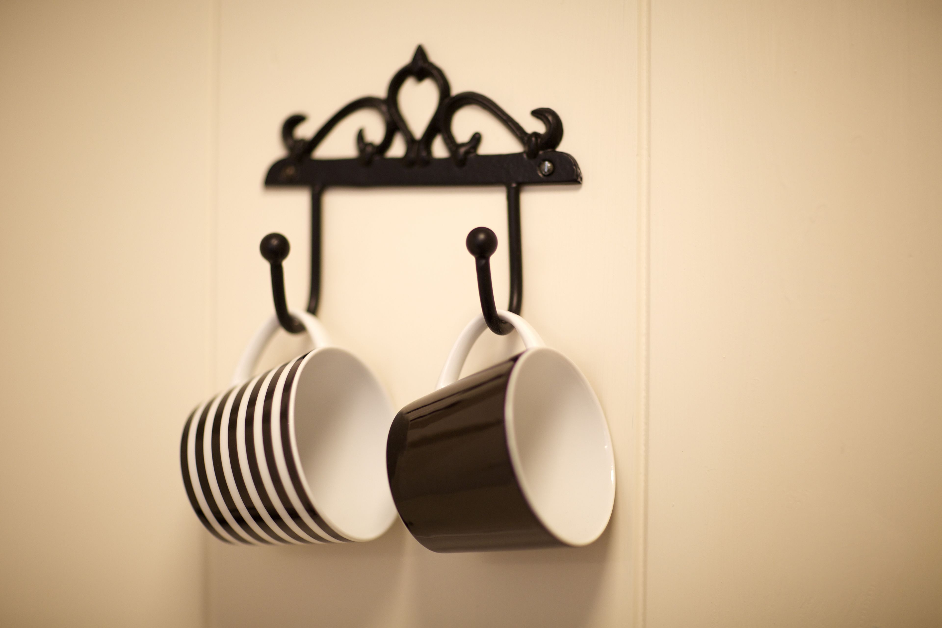 A black metal rack with two white mugs hanging from it.