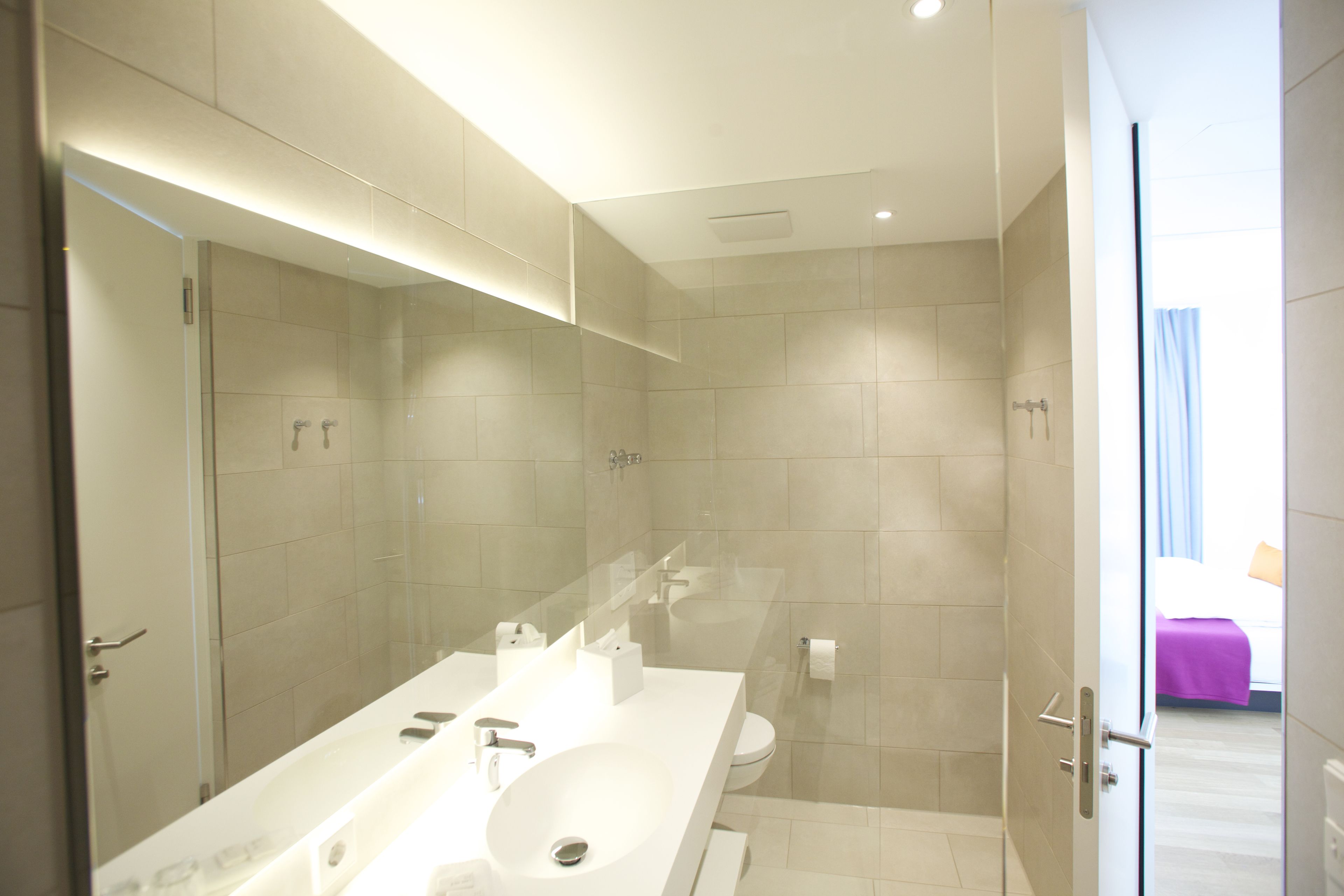 A modern bathroom with a large sink, mirror, and shower.