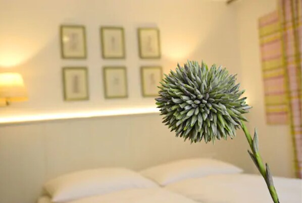 Una habitación con una cama, una pared adornada con cuadros y una planta en maceta.