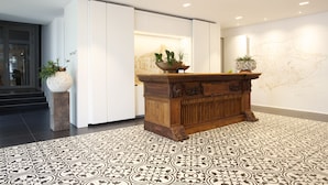 Un hall d’entrée avec un comptoir de réception en bois, un sol à motifs et une carte accrochée au mur.