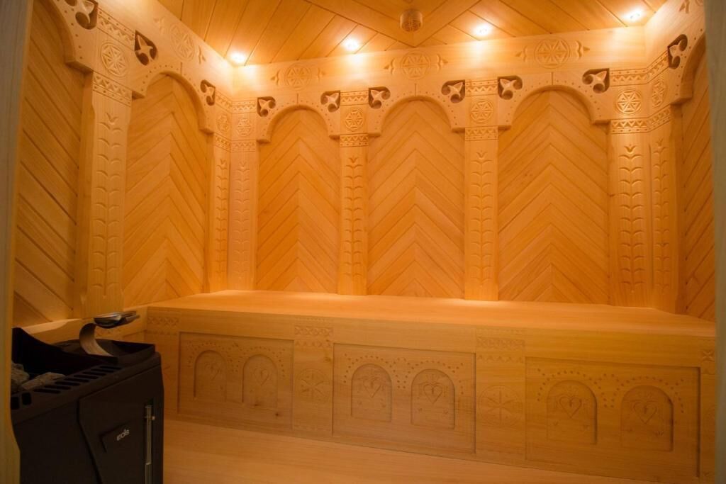 A room with a large, freestanding bathtub, wooden paneling with geometric patterns, and a ceiling with recessed lighting.