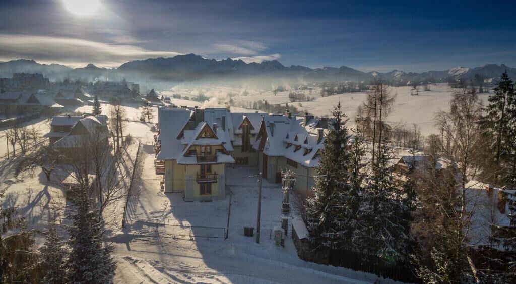 Un village enneigé, avec des bâtiments traditionnels et une vue dégagée sur les montagnes lointaines.
