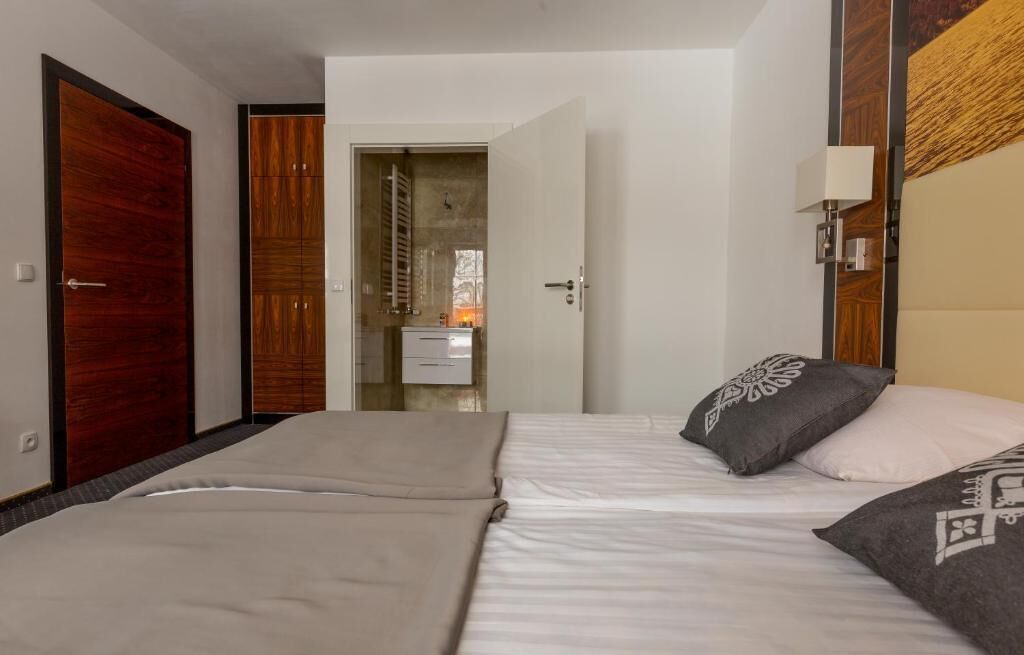 A hotel room with a bed, a wardrobe, and a bathroom visible through an open door.