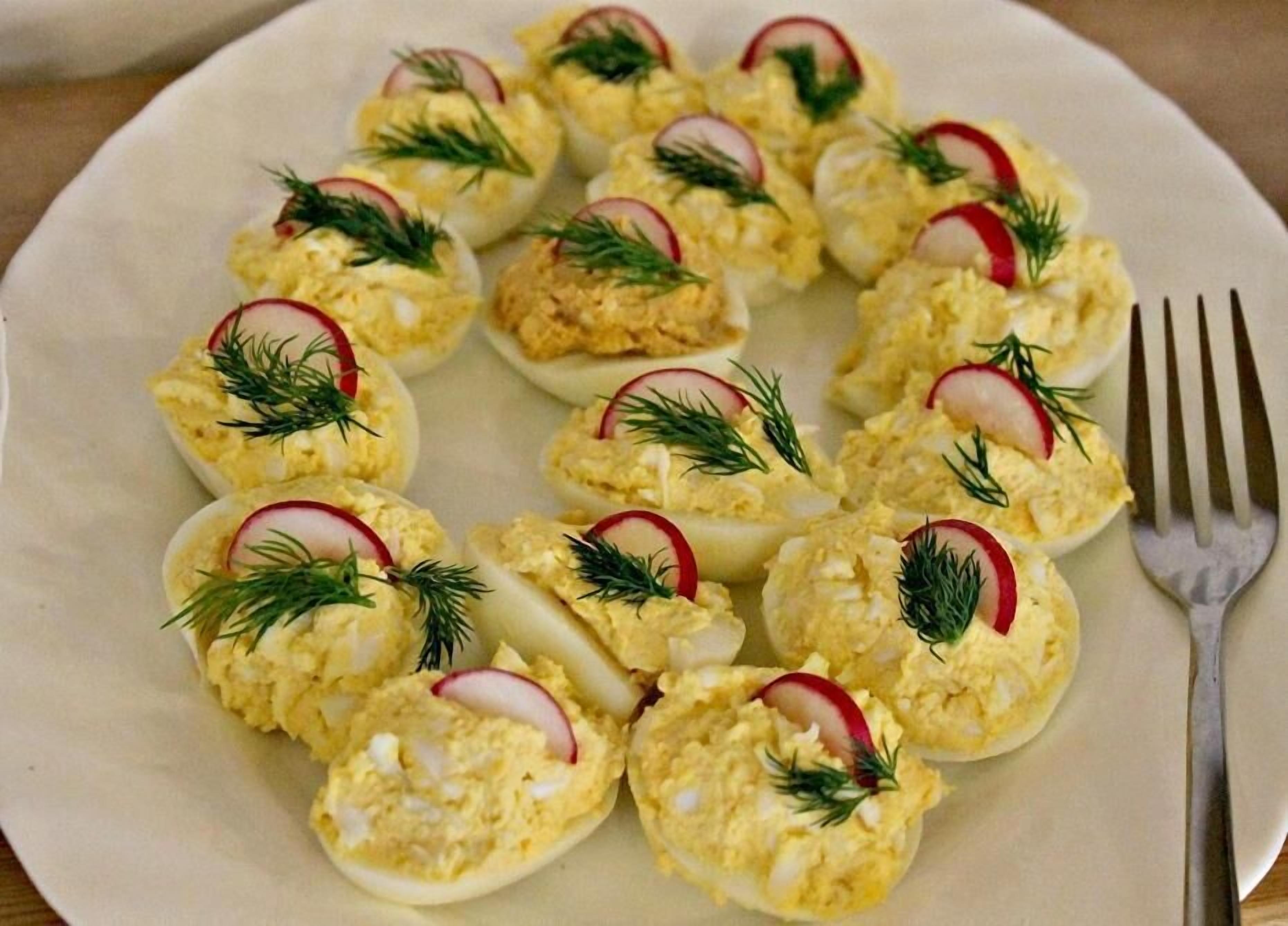 A plate of deviled eggs garnished with radish slices and dill.