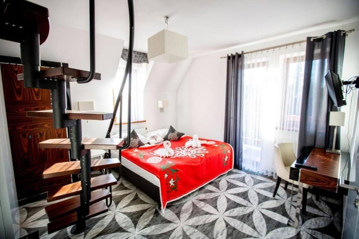 A modern hotel room with a bed, a desk, and a staircase.