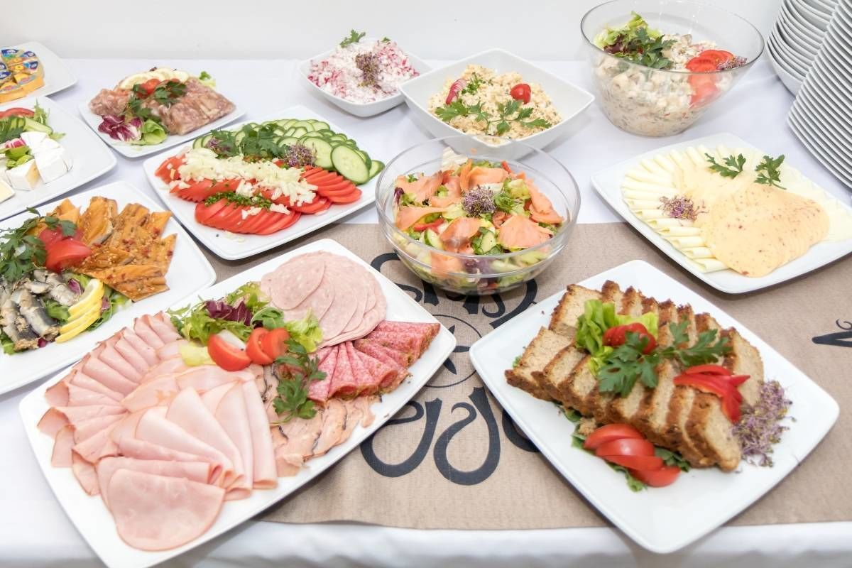 Un assortiment de produits alimentaires, notamment des viandes en tranches, des salades et un bol de salade au saumon.