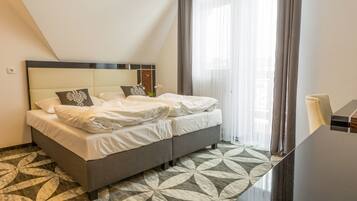 Een netjes opgemaakt bed met witte lakens en decoratieve kussens, een modern hoofdbord en een vloer met een patroon.