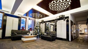 A spacious living area with two black sofas, a wooden coffee table, and a large decorative light fixture on the ceiling.