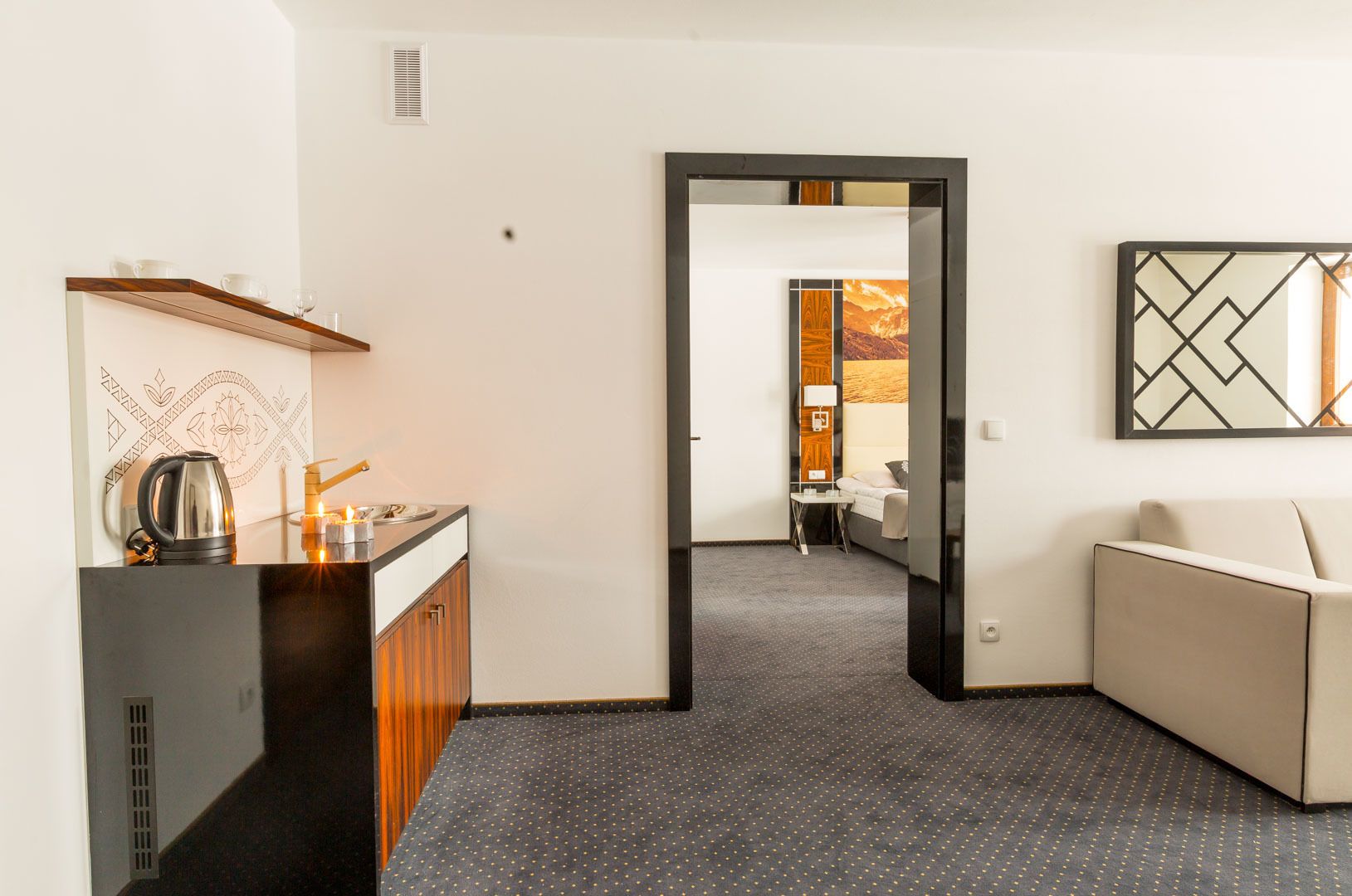A hotel room with a kitchenette, a bed, a seating area, and a view of the outside.