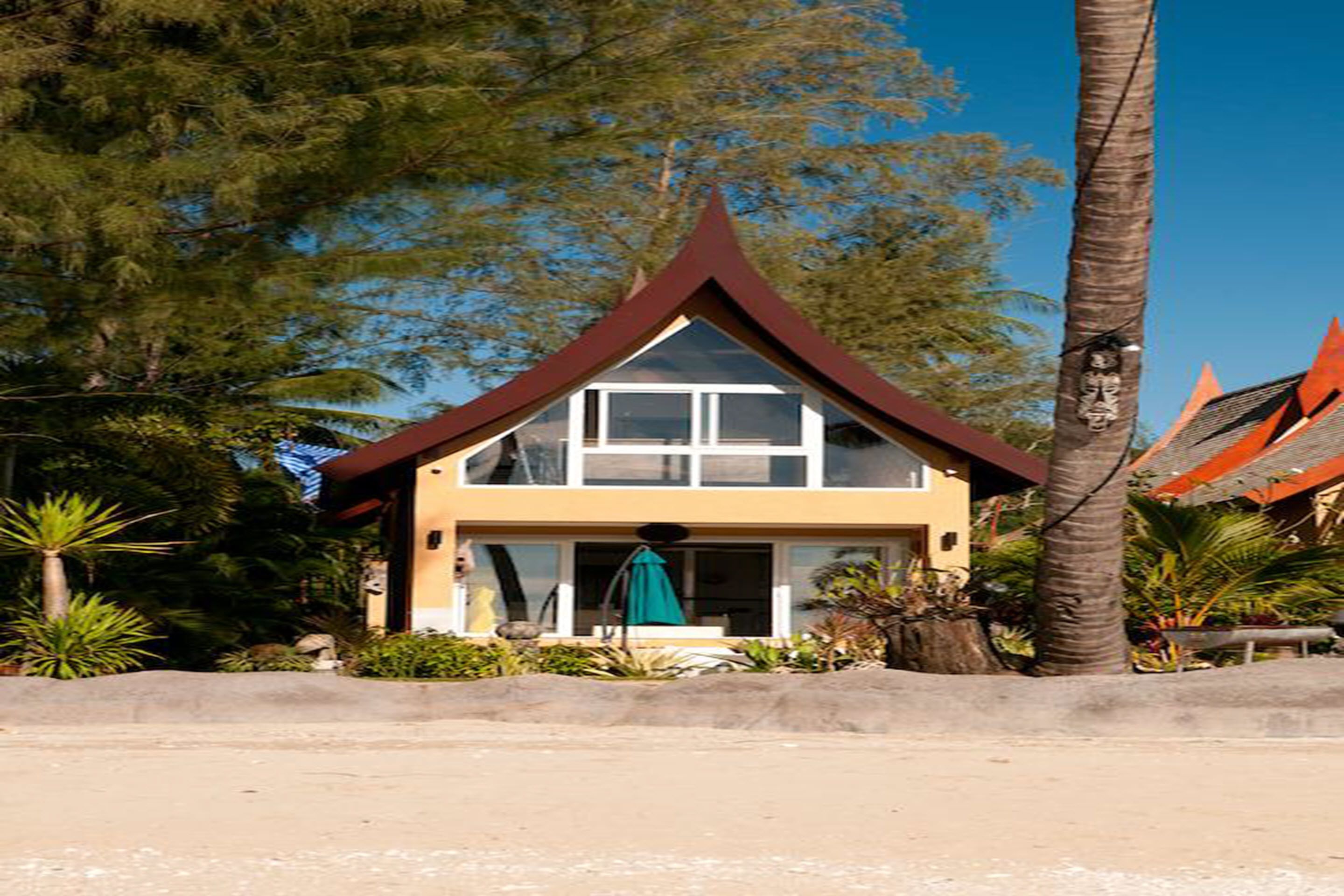 A two-story building with a steeply pitched roof, surrounded by tropical vegetation.