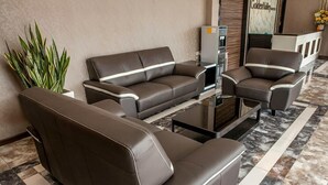 A modern reception area with a sofa set, a coffee table, and a plant. - Golden Valley Hotel (Malacca City)