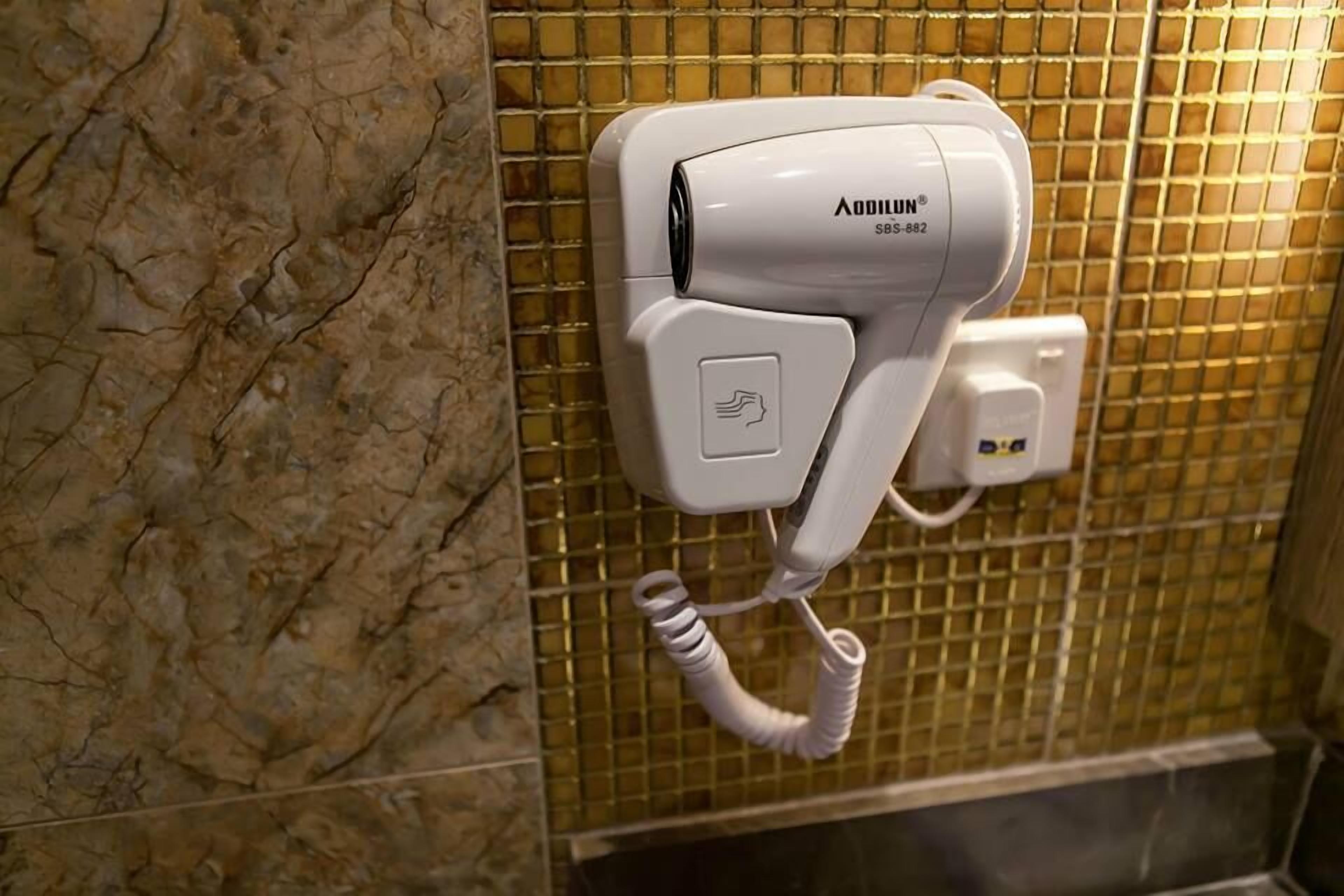 A hair dryer mounted on a tiled wall in a bathroom.