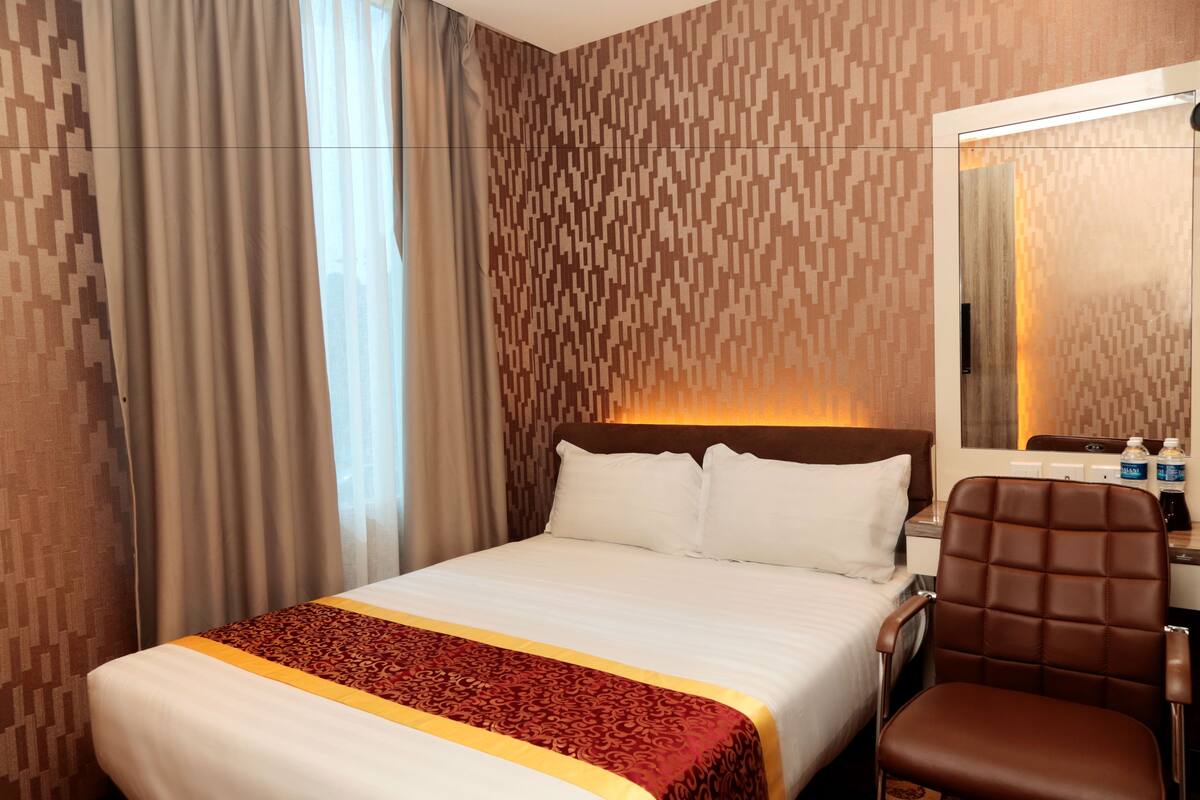 Una habitación de hotel con una cama grande, un escritorio con silla y un espejo.