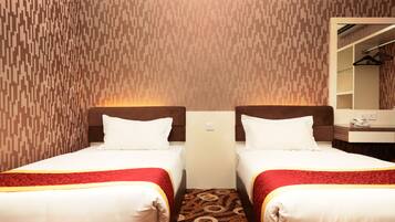 A hotel room with two beds, a mirror, a dresser, and a patterned carpet.