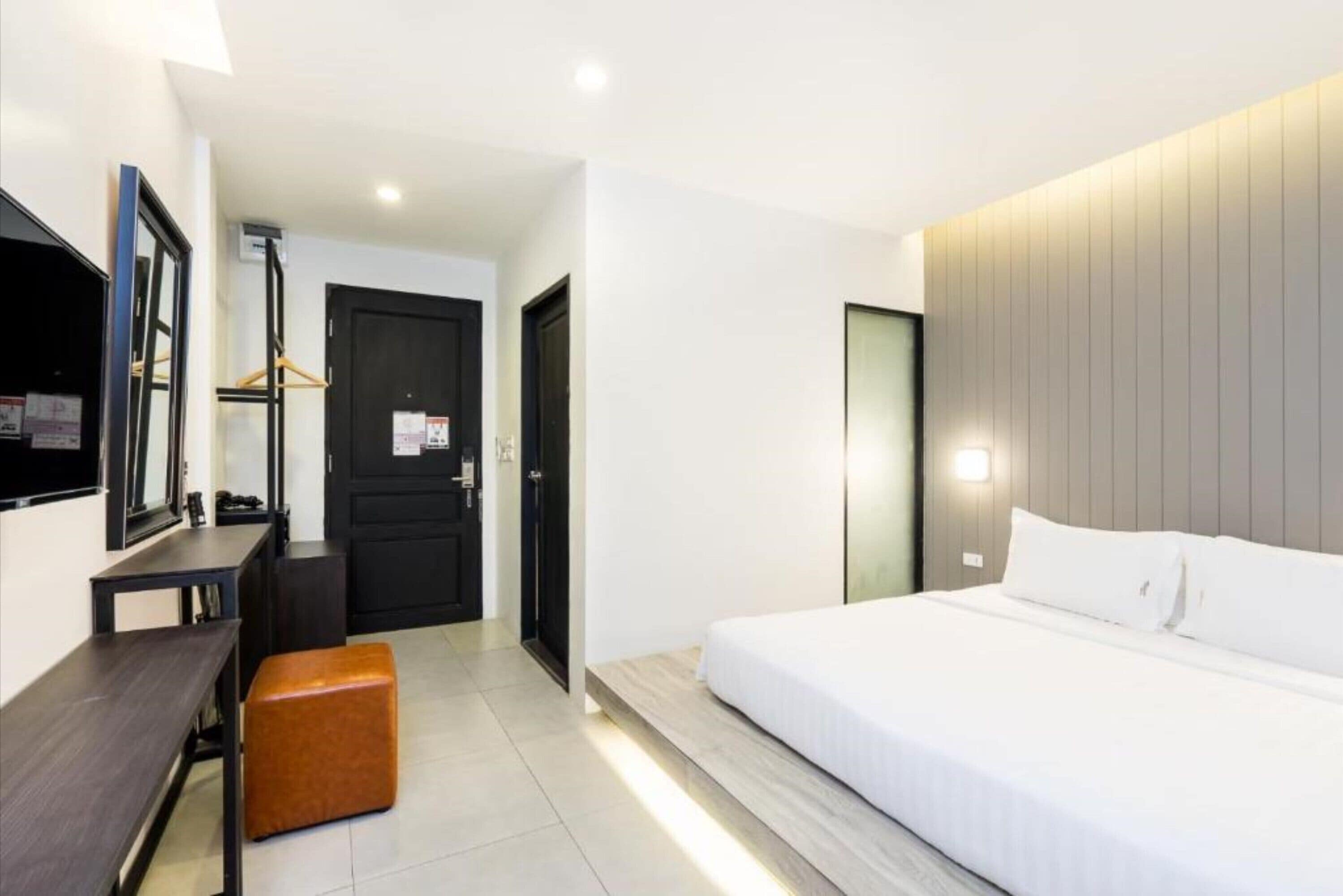 Una moderna camera d'albergo con un letto, una scrivania, una sedia e un armadio.