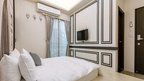 Een slaapkamer met een bed, een televisie, een airconditioning en een deur.