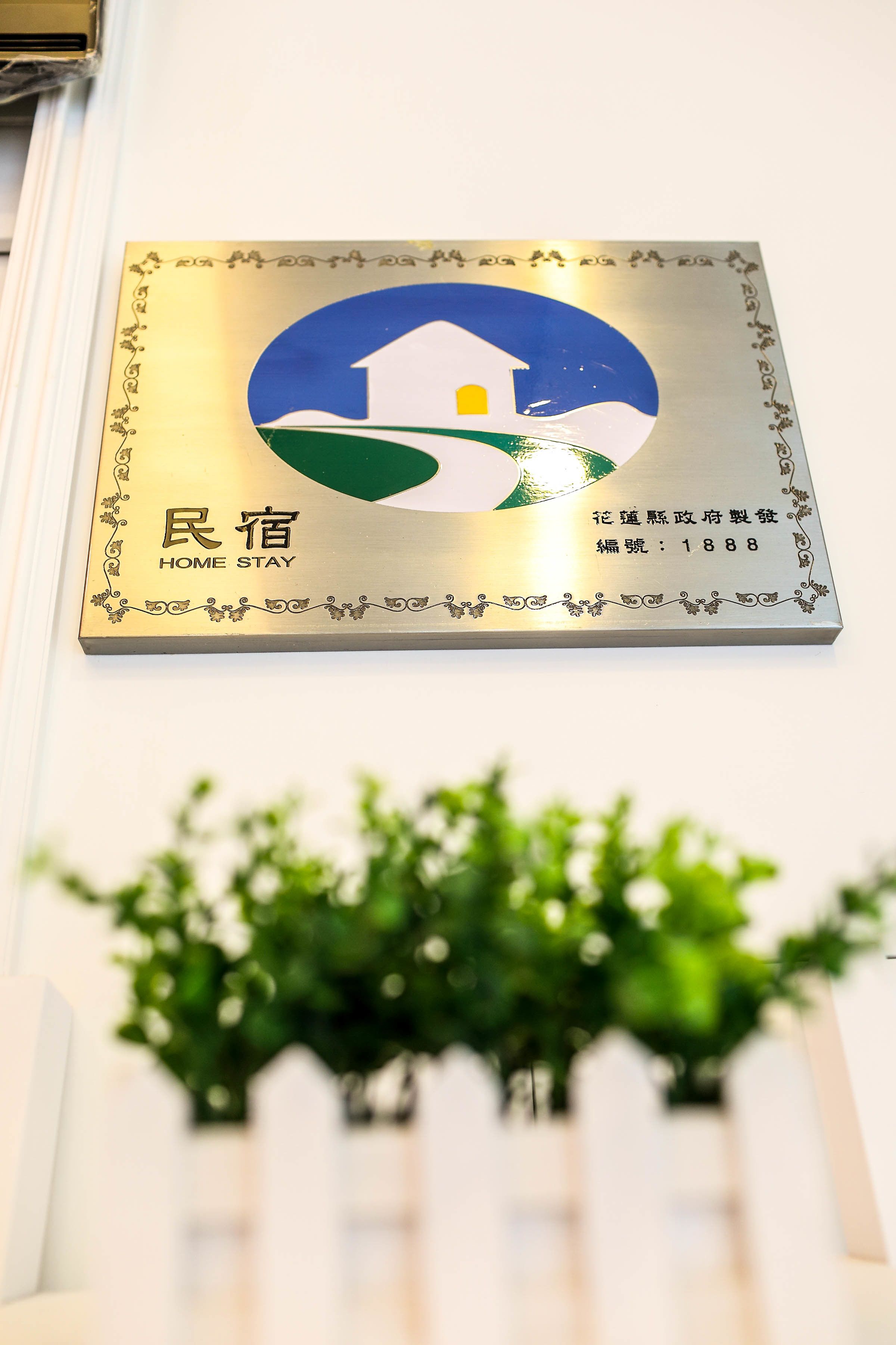Una placa con el logotipo de una casa y texto que indica "Home Stay" y el número "1888".