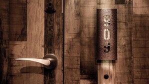 Una puerta de madera con picaporte de metal y timbre.