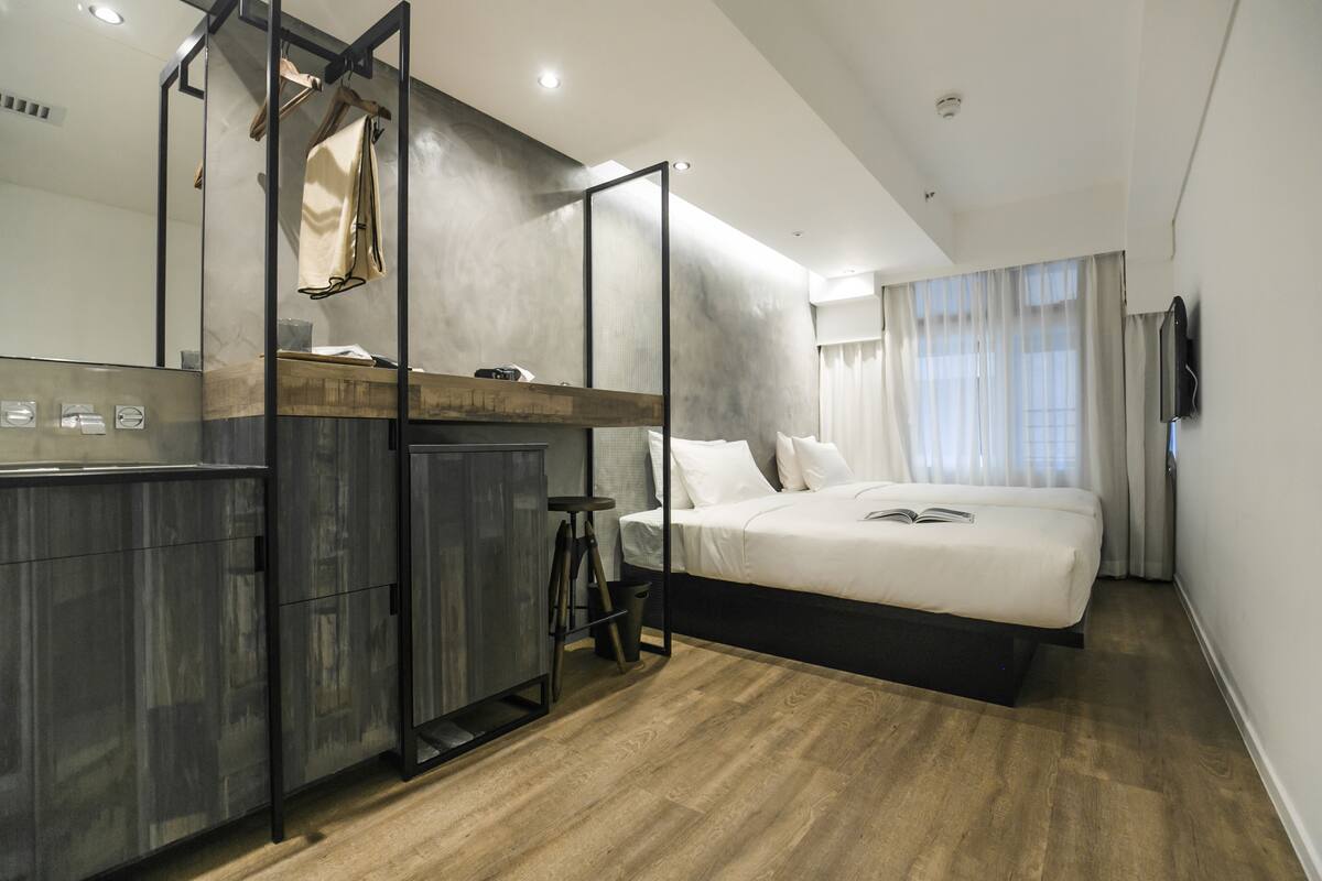 Un dormitorio moderno con una cama grande, un armario de madera, una mesita pequeña y un espejo.