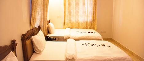 A hotel room with two beds, a wooden headboard, a telephone, and a window with curtains.