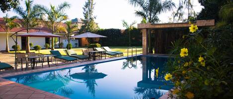 Una piscina al aire libre, sombrillas, tumbonas