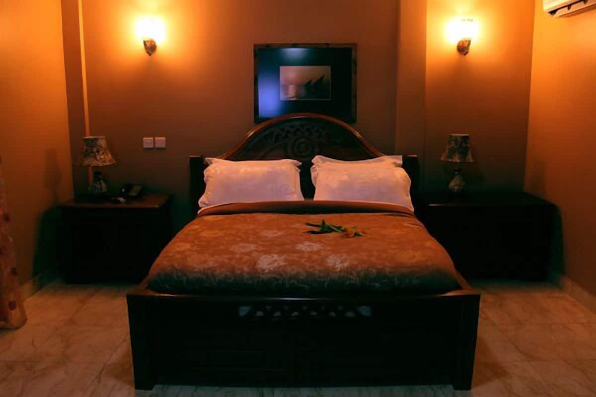 A bedroom with a bed, two bedside tables, and wall-mounted lamps.