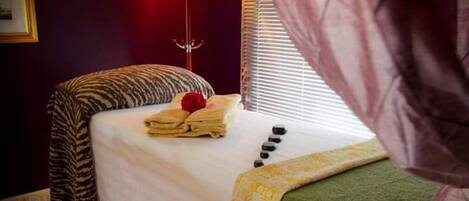 A neatly made bed with a zebra-patterned blanket, a folded towel, and a red object on the bed.
