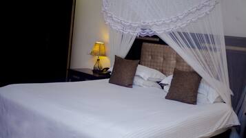 A neatly made bed with a canopy, a bedside lamp, and two pillows.