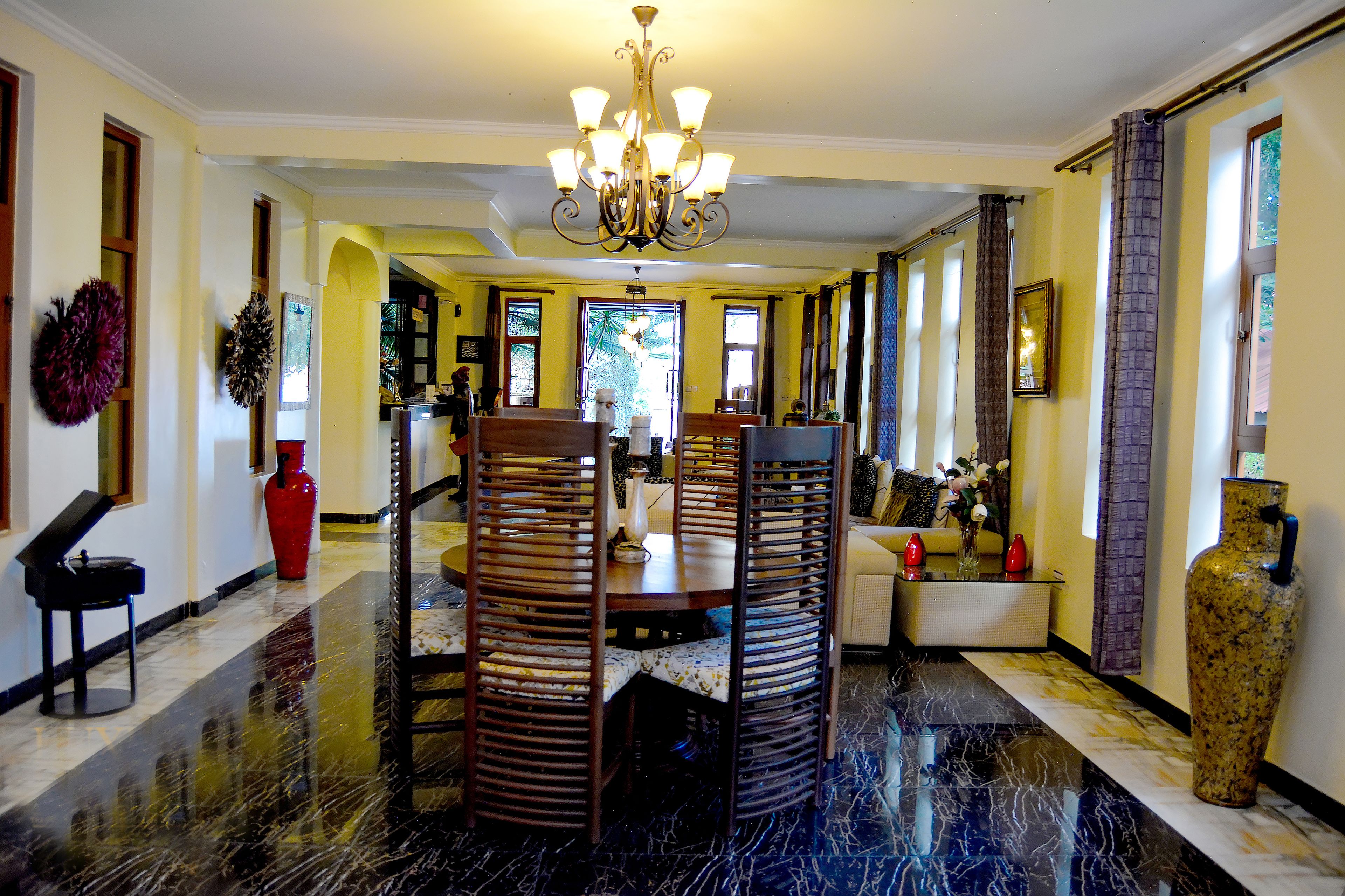 A spacious lobby with a marble floor, a chandelier, and a seating area with a sofa and chairs.