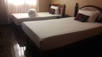 Two single beds with white linens, a wooden headboard, and a telephone on the nightstand.