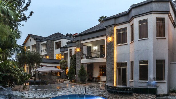 A multi-story residential building with a swimming pool, outdoor seating, and a well-lit exterior. - Elevate Suites (Kigali)