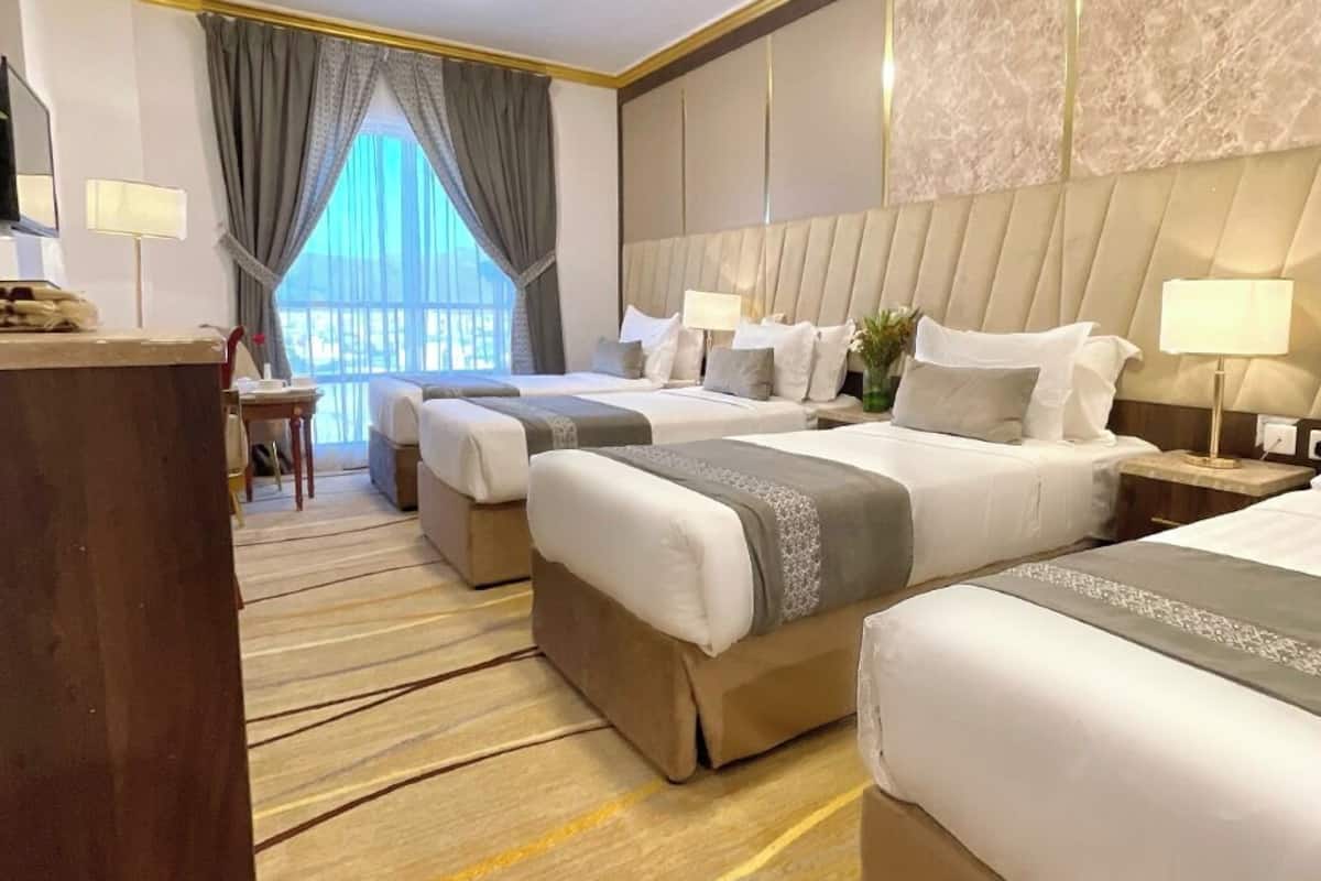 Hotellihuone, jossa on kaksi sänkyä, työpöytä ja näkymä ulos.