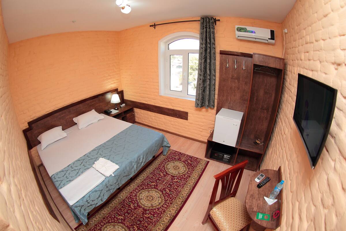 A bedroom with a bed, a desk, a chair, a TV, and a wardrobe.