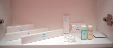 A hotel bathroom with a white sink, a shower cap, and a vanity kit.