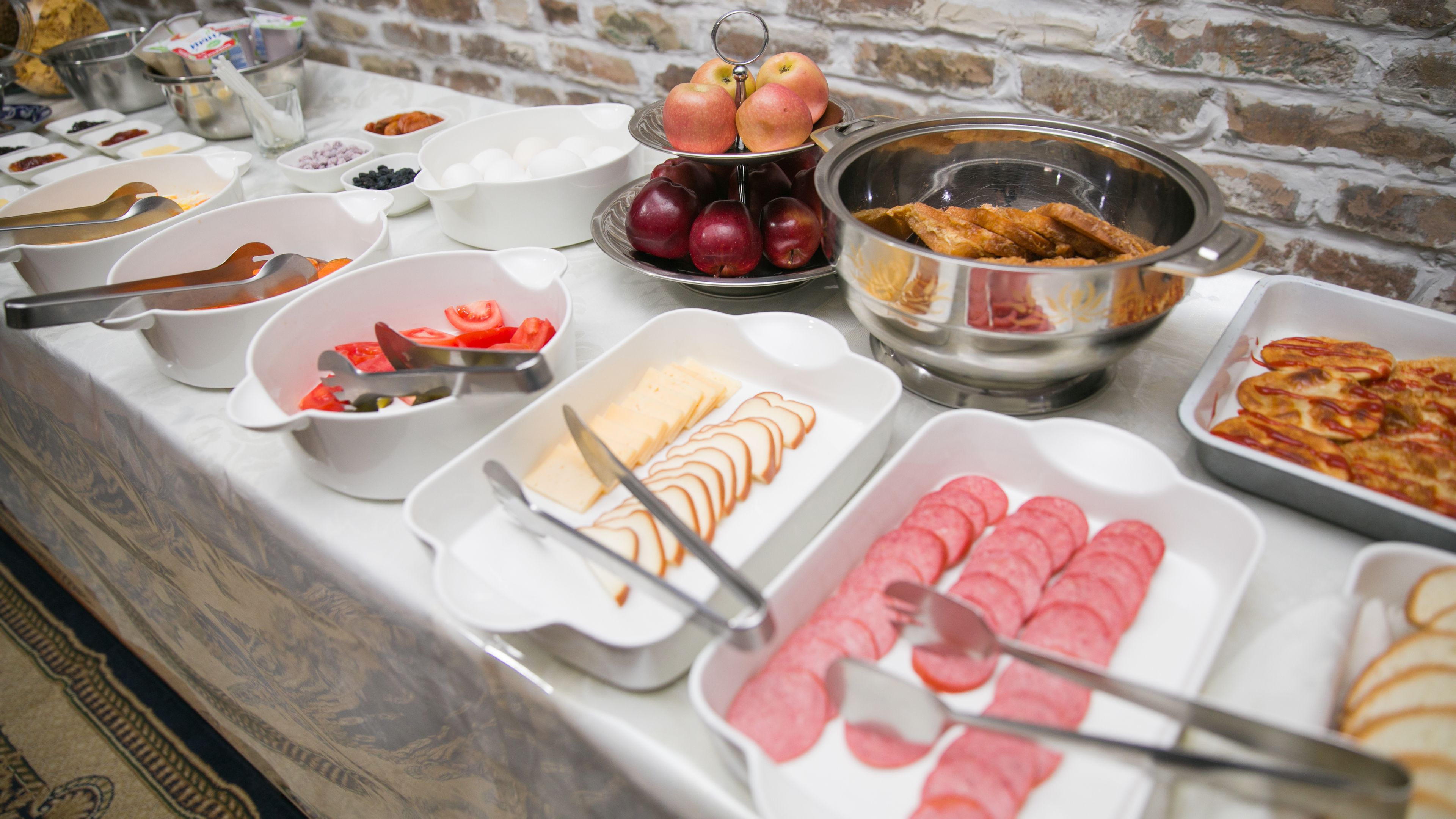 A buffet with various food items including sliced apples, cheese, and meats.