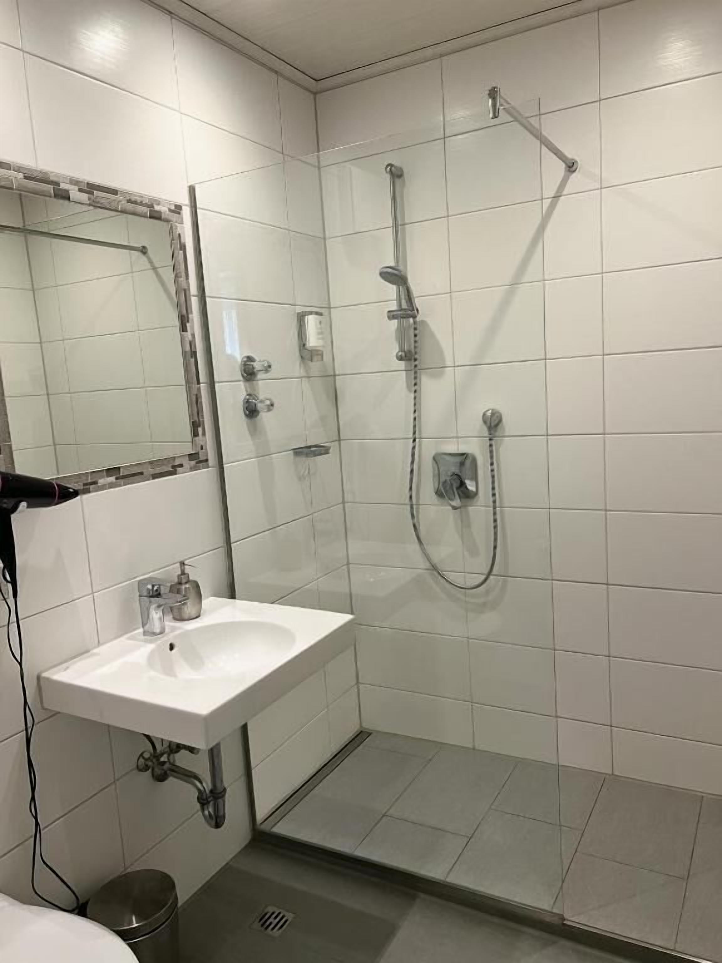 A bathroom with a white sink, a mirror, and a glass-enclosed shower area.