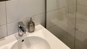 A modern bathroom with a glass shower enclosure, a white sink with a chrome faucet, and a towel rack with a folded towel. - Hotel Garni Illertal (Altenstadt)