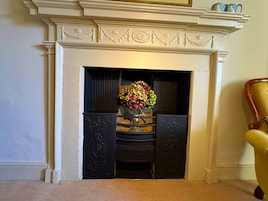Una chimenea con una repisa decorativa y un jarrón con flores.
