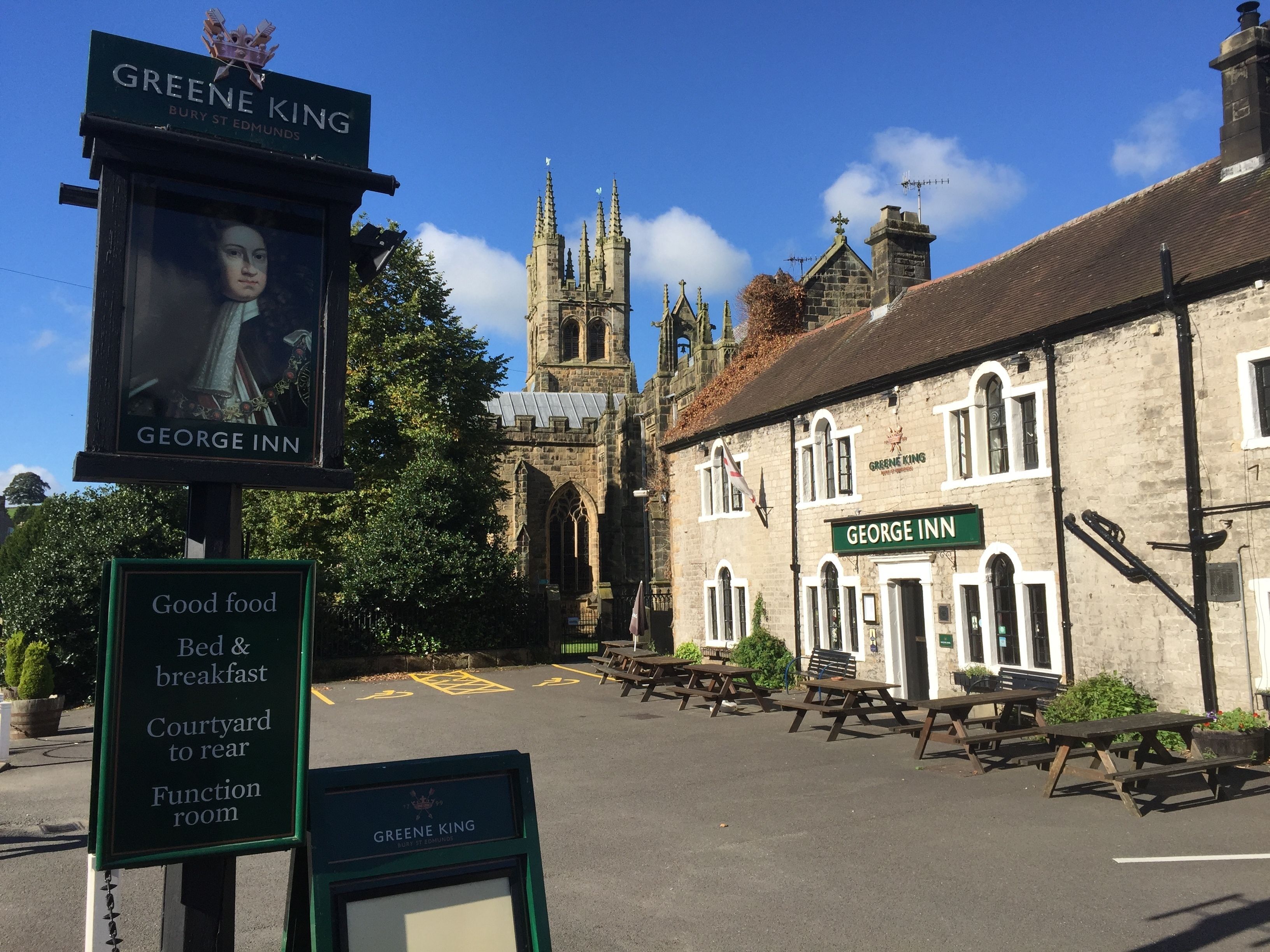Un bâtiment historique portant une enseigne indiquant « George Inn » et une autre indiquant « Greene King ».
