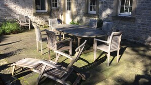 A stone building with a round wooden table and six chairs. - The Old Vicarage B&B (Buxton)