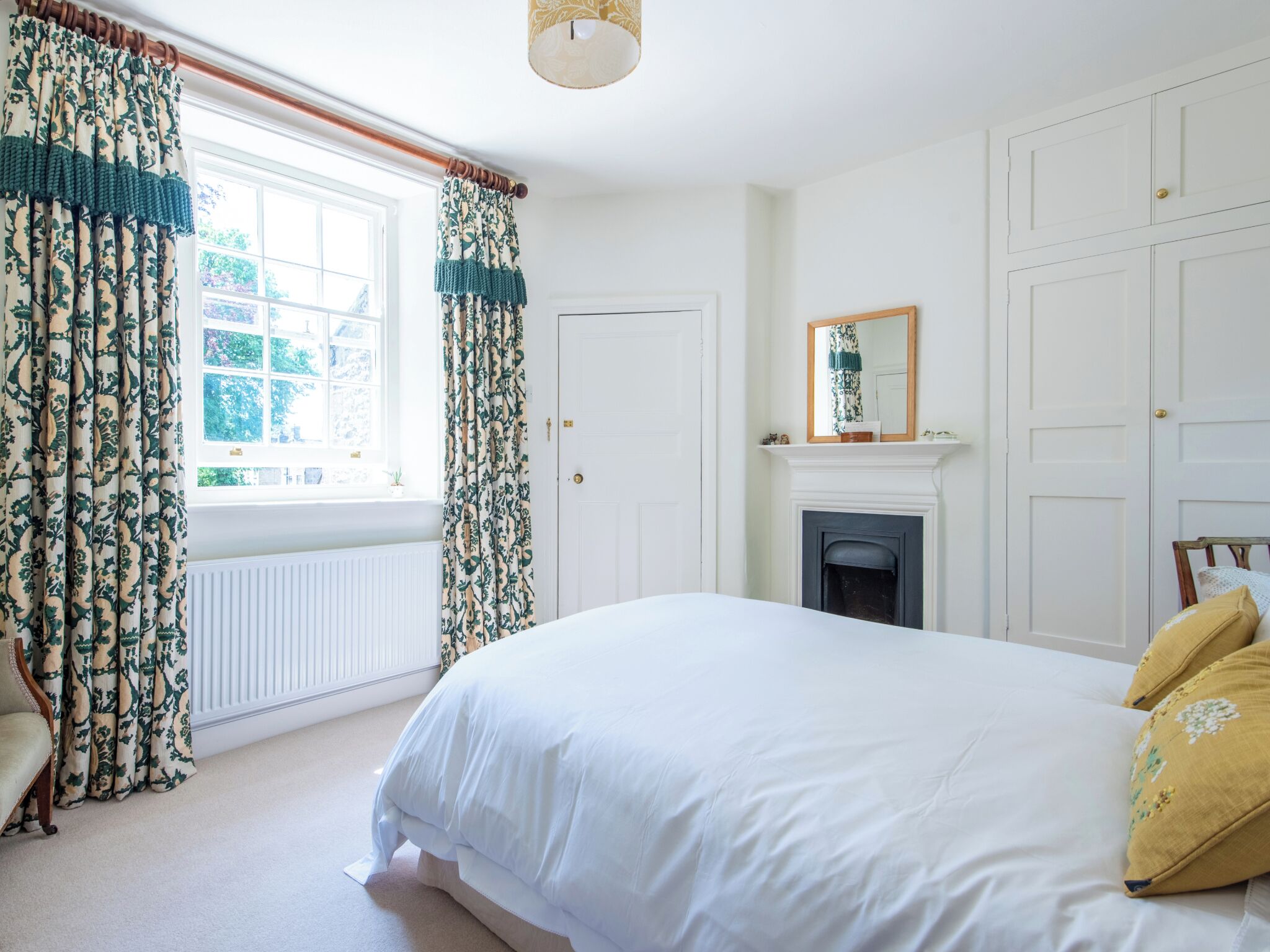 A bedroom with a large bed, a fireplace, and a window with curtains.