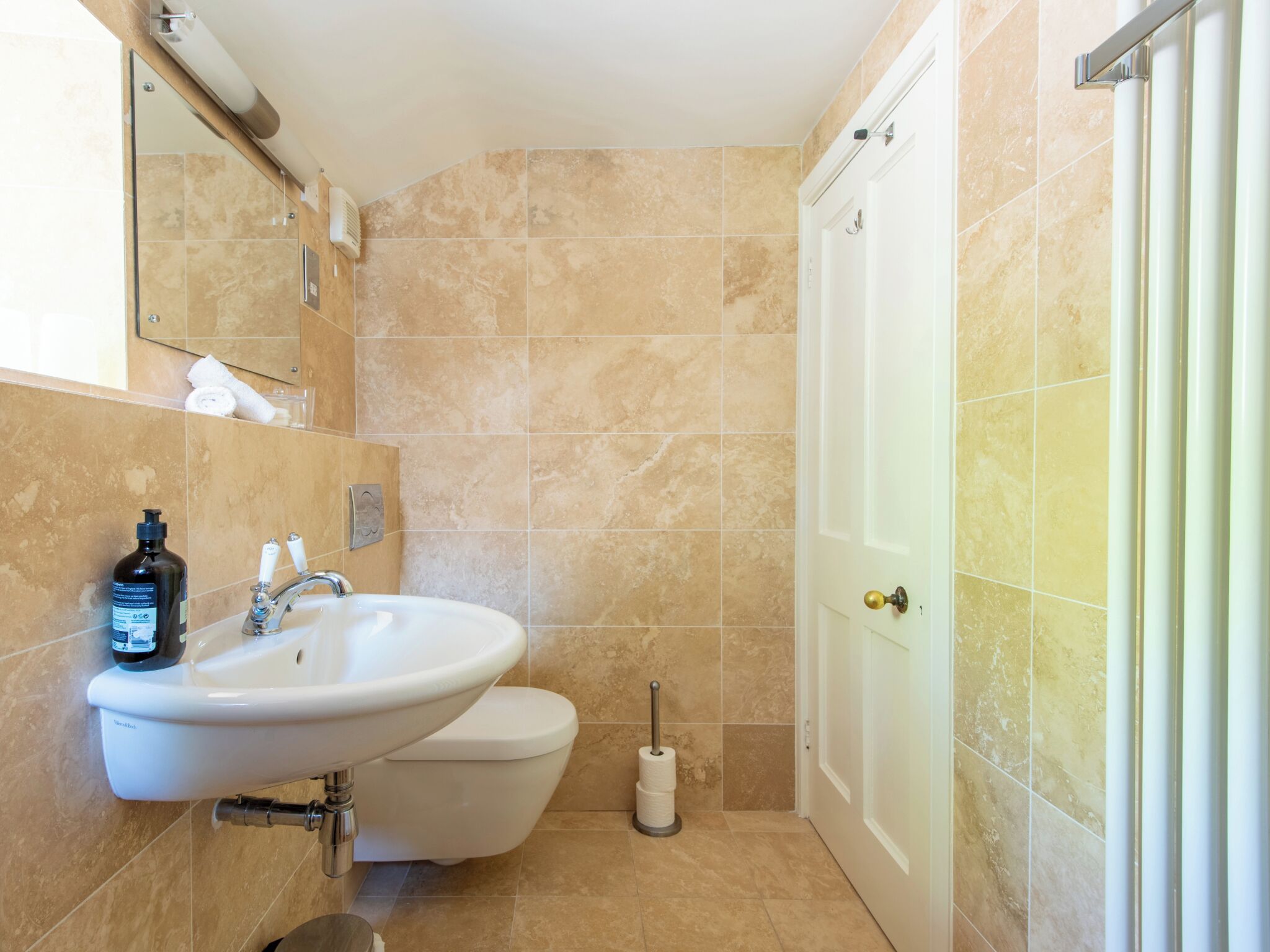 Un baño con lavamanos, inodoro y zona de ducha.