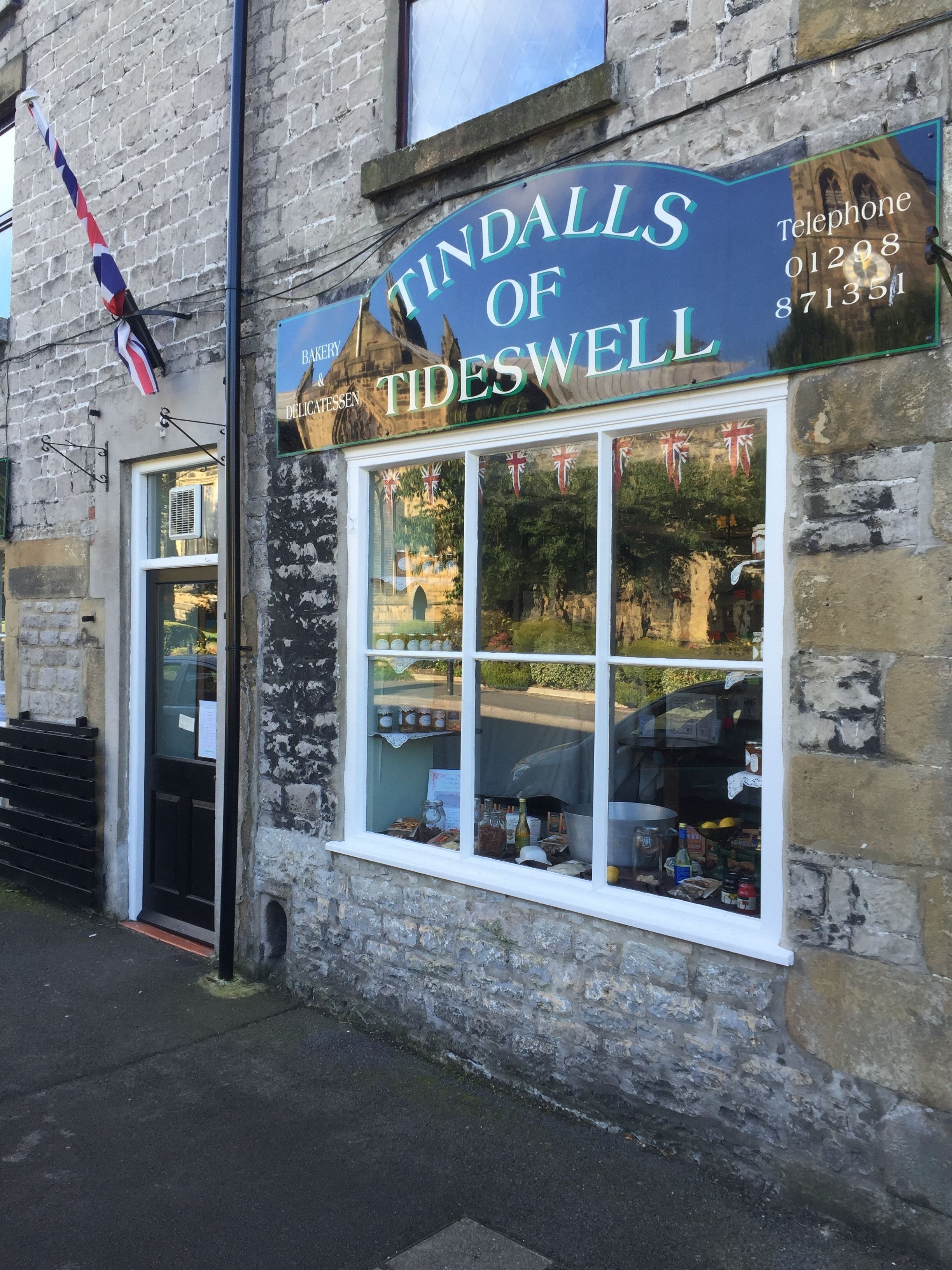 A building with a sign reading "Tindalls of Tideswell" and a telephone number.