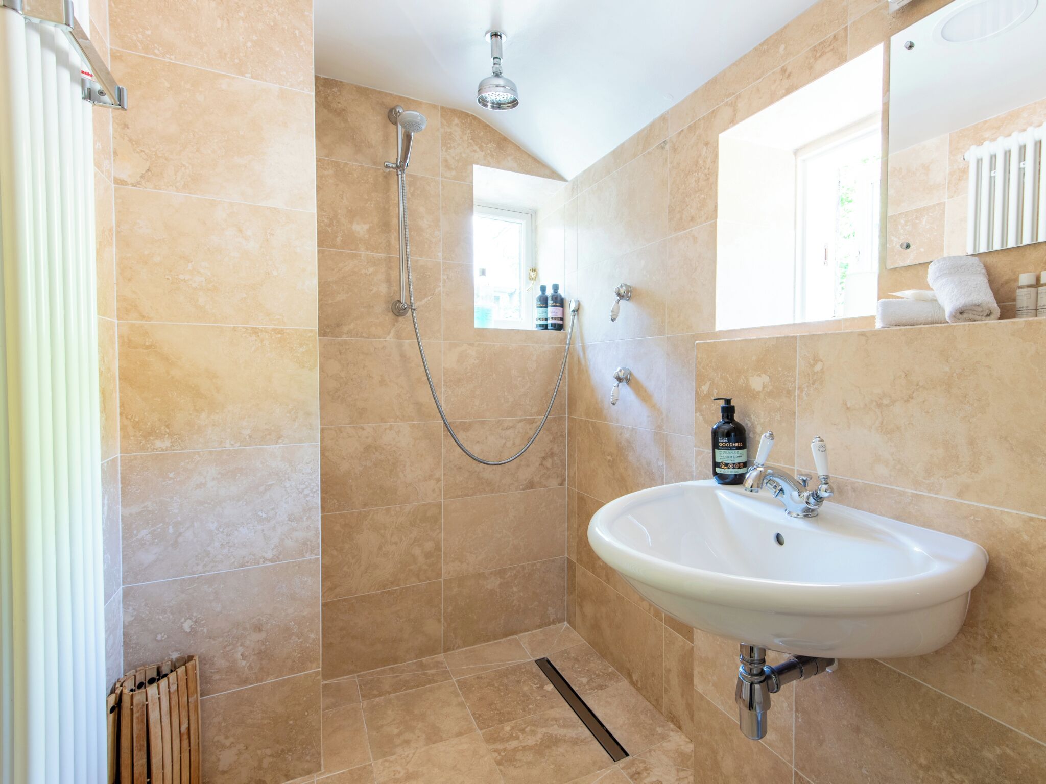 A bathroom with a shower, a sink, and a window.